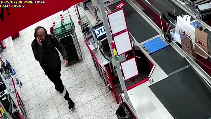 Mężczyzna w sklepie, przy kasie. Złodziej.